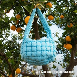 Auf dem Bild sieht man eine hellblaue Tasche, die an einem Ast in einem Orangenbaum hängt. Das Bild ist vom Instagram Account von @KAUFDICHGLUECKLICH; Zur abgebildeten Tasche gehen
