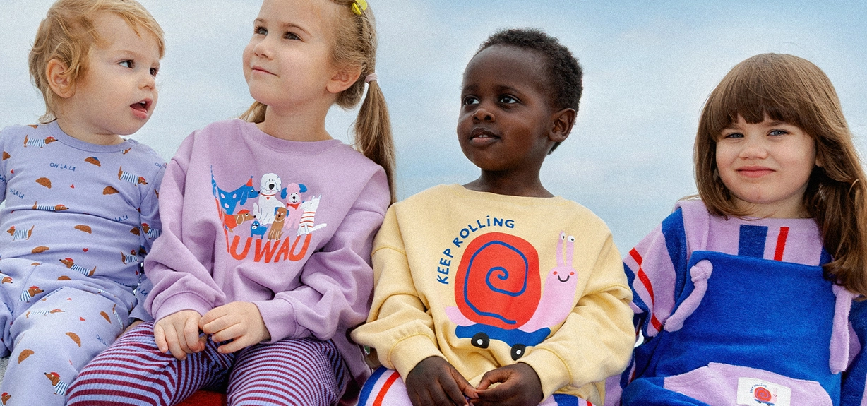 Kinder mit Tischtennisschlägern, die auf einer Tischtennisplatte sitzen.